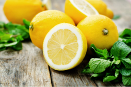 Sliced fresh lemon with juicy segments and green mint leaves on a rustic wooden table, highlighting vibrant citrus fruits and natural ingredients for healthy recipes and refreshing beverages