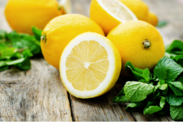 Sliced fresh lemon with juicy segments and green mint leaves on a rustic wooden table, highlighting vibrant citrus fruits and natural ingredients for healthy recipes and refreshing beverages