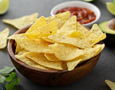 Close-up of tortilla chips with avocado in background, representing snack ingredient solutions